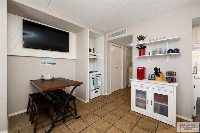 110 E Pompano St, South Padre Island, TX 78587 - kitchen with electric range, open shelves, light countertops, white cabinetry, and tile patterned floors
