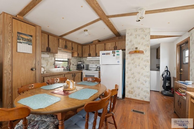 kitchen featuring lofted ceiling with beams, sink, wood-type flooring, and white appliances