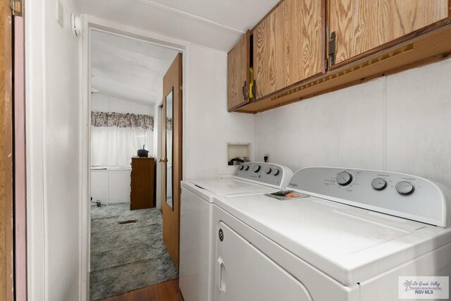 clothes washing area featuring cabinets, washing machine and dryer, and hardwood / wood-style flooring