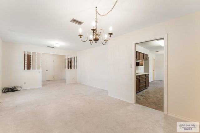 spare room featuring an inviting chandelier