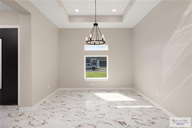 unfurnished dining area featuring a notable chandelier and a raised ceiling