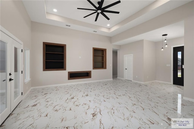 unfurnished living room with ceiling fan and a tray ceiling