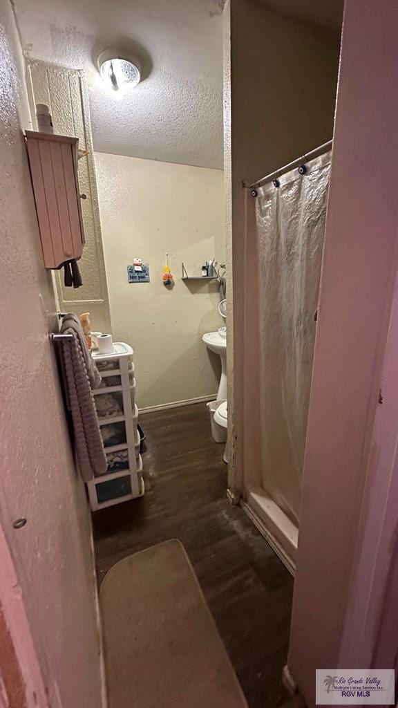 bathroom featuring a shower with curtain, wood-type flooring, toilet, and a textured ceiling