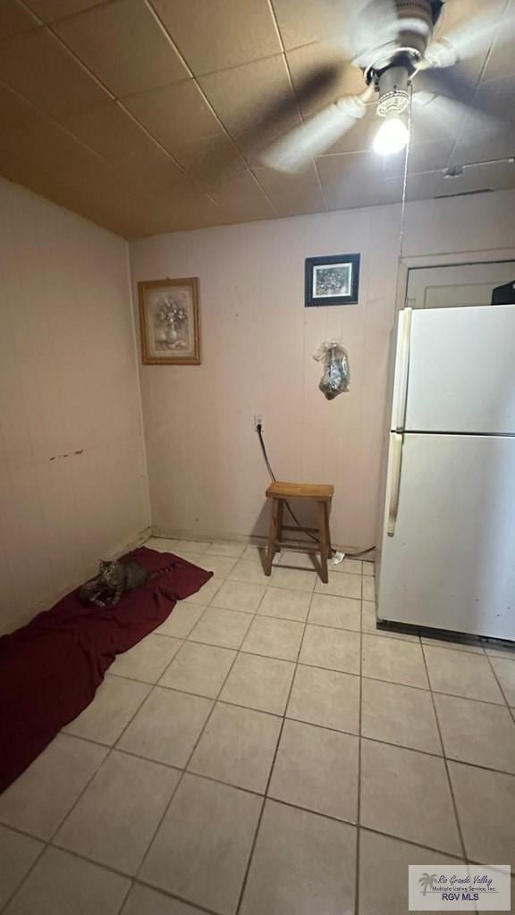 interior space with white refrigerator, light tile patterned floors, and ceiling fan