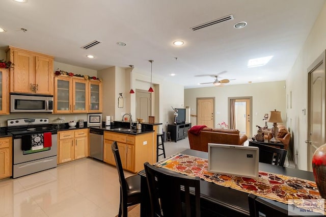 kitchen featuring a kitchen breakfast bar, sink, ceiling fan, light tile patterned floors, and stainless steel appliances