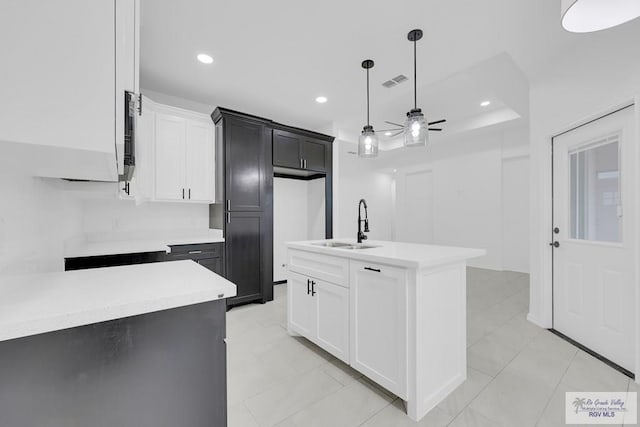 kitchen featuring white cabinetry, sink, hanging light fixtures, a kitchen island with sink, and ceiling fan