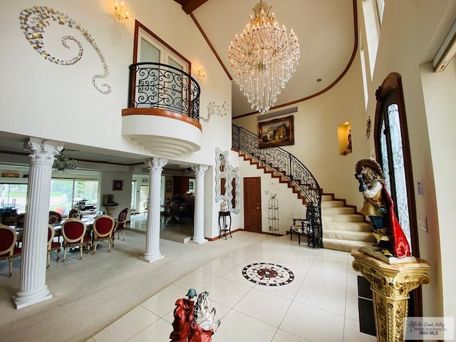 foyer entrance featuring decorative columns, carpet flooring, and a towering ceiling