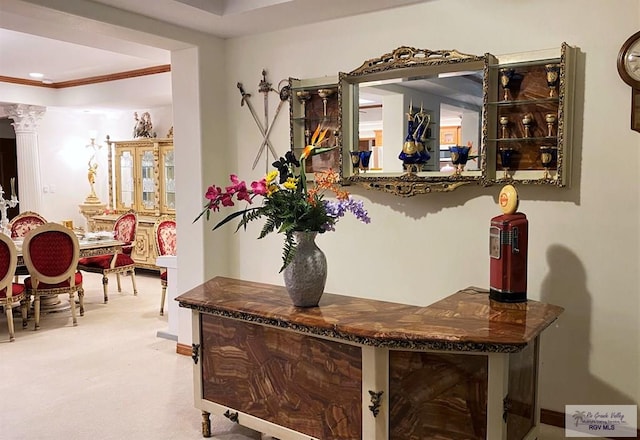 bar featuring ornate columns, crown molding, and carpet floors