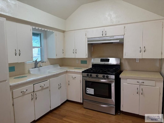 54 Shary Ave, Brownsville, TX 78521 - kitchen with gas range, under cabinet range hood, lofted ceiling, wood finished floors, and tasteful backsplash