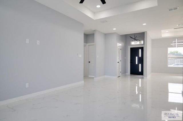 interior space with ceiling fan with notable chandelier, a raised ceiling, and elevator