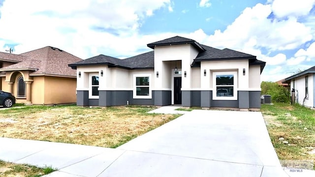 prairie-style house featuring central air condition unit and a front lawn