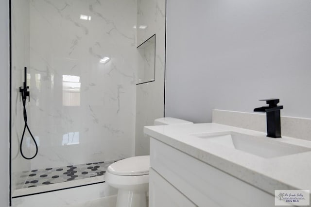 bathroom featuring a tile shower, vanity, and toilet