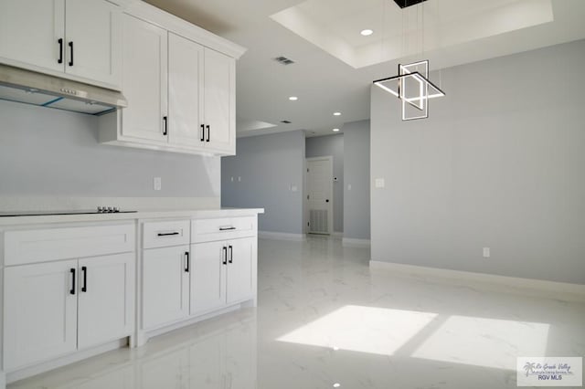 kitchen with a tray ceiling, black electric stovetop, white cabinets, and hanging light fixtures