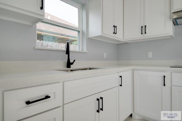 kitchen featuring white cabinets, extractor fan, light stone countertops, and sink