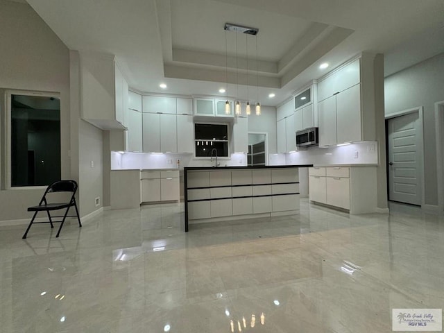 kitchen with white cabinets, sink, a raised ceiling, and hanging light fixtures