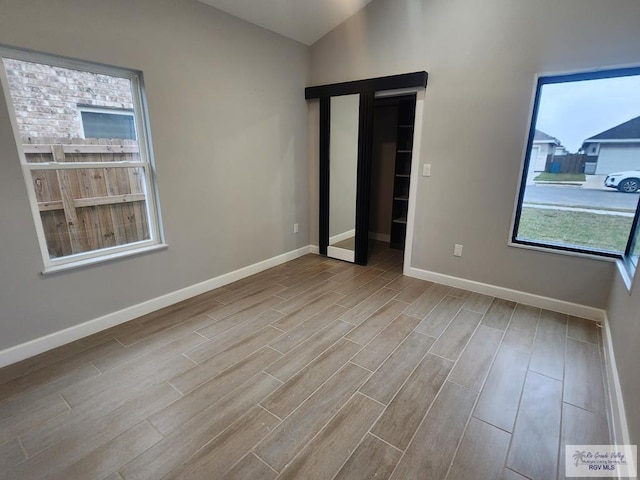 unfurnished room featuring light wood-type flooring and vaulted ceiling