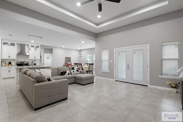 living room with baseboards, a raised ceiling, and light tile patterned flooring