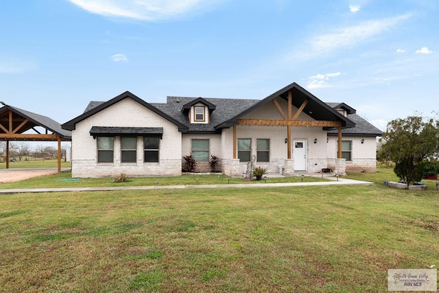 view of front facade with roof with shingles, a front lawn, and brick siding