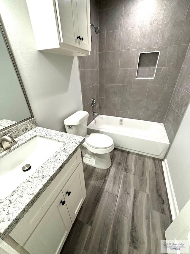 full bathroom with hardwood / wood-style flooring, vanity, toilet, and tiled shower / bath