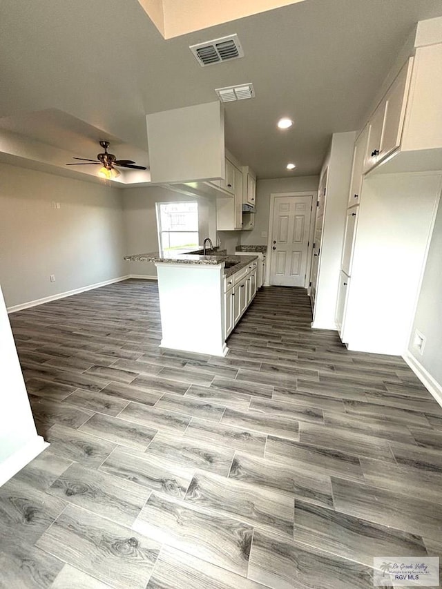 kitchen with sink, ceiling fan, dark stone countertops, light hardwood / wood-style floors, and white cabinetry