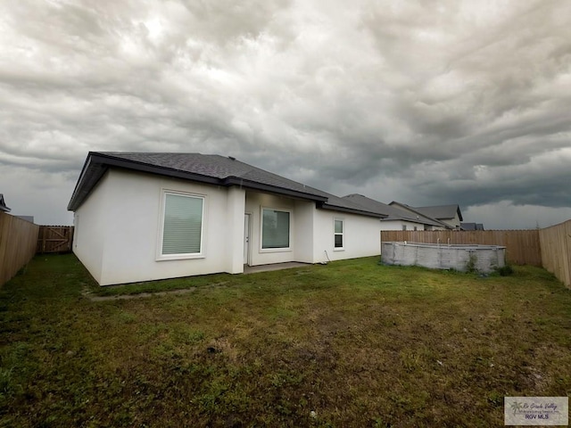 rear view of property featuring a fenced in pool and a yard