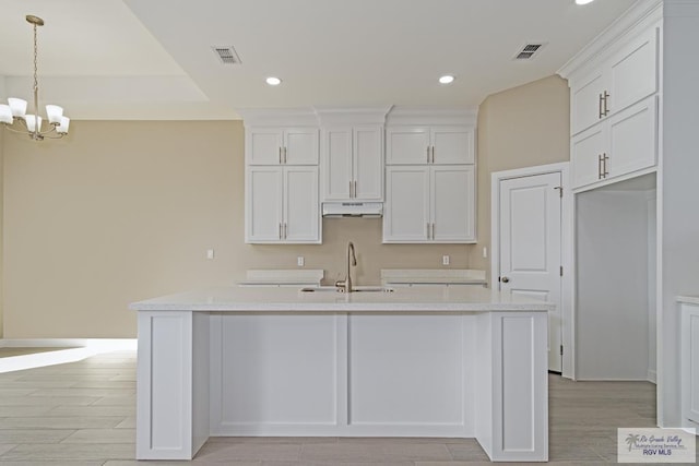 kitchen featuring white cabinetry, an island with sink, and an inviting chandelier