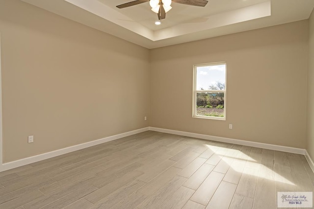 unfurnished room with a tray ceiling, light hardwood / wood-style flooring, and ceiling fan