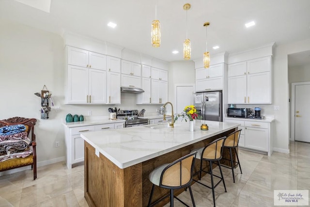 6221 Grapevine Loop, Brownsville, TX 78526 - kitchen featuring stainless steel appliances, under cabinet range hood, recessed lighting, white cabinetry, and a kitchen bar
