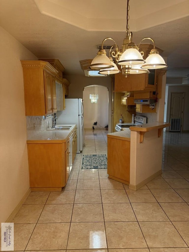 kitchen featuring hanging light fixtures, a notable chandelier, kitchen peninsula, white appliances, and a breakfast bar