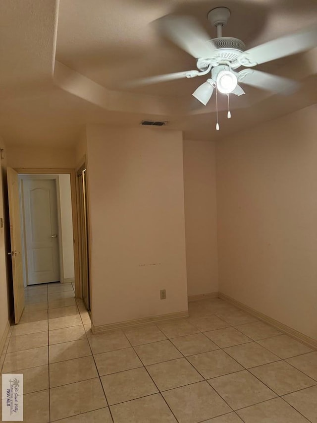 empty room with ceiling fan and light tile patterned floors