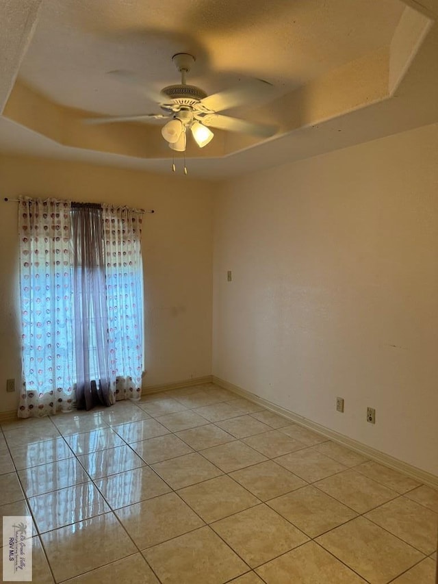 unfurnished room featuring ceiling fan, a raised ceiling, and light tile patterned floors