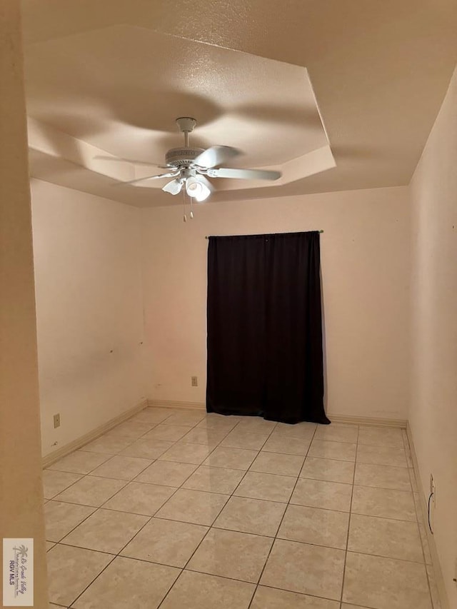 tiled spare room with ceiling fan, a raised ceiling, and a textured ceiling