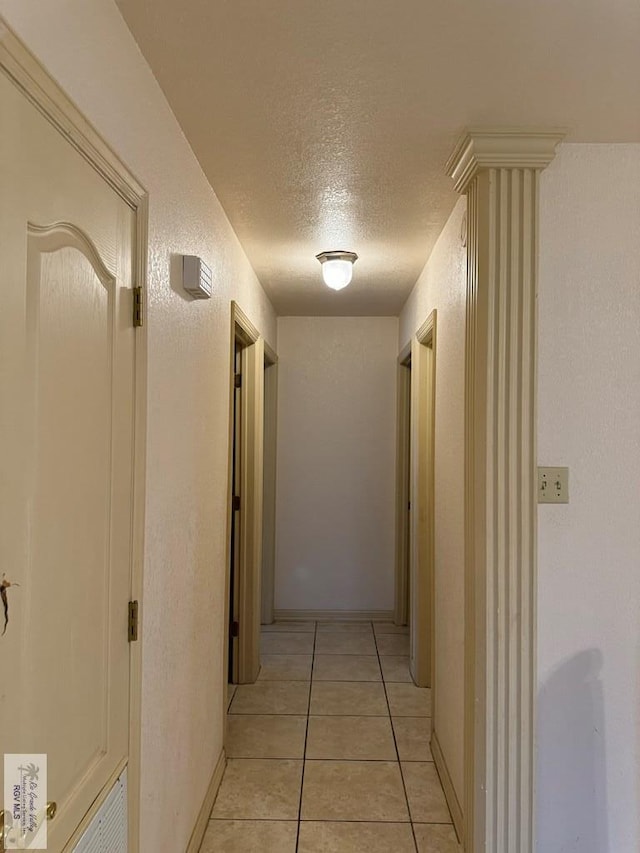 corridor featuring light tile patterned floors and a textured ceiling