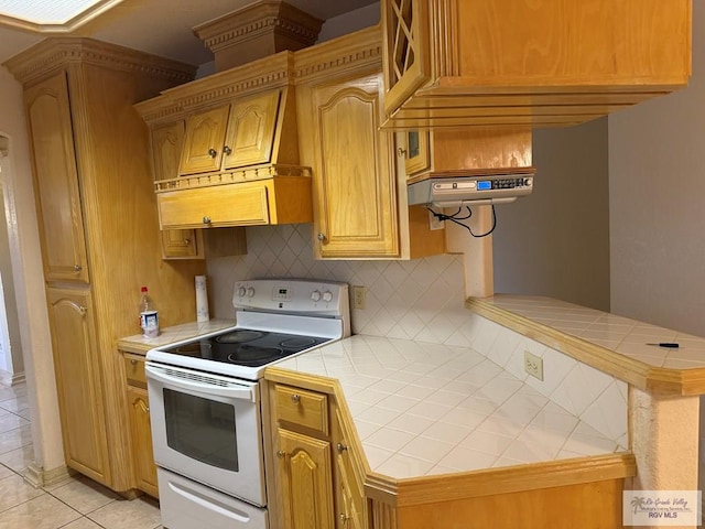 kitchen featuring decorative backsplash, kitchen peninsula, light tile patterned floors, electric range, and tile counters