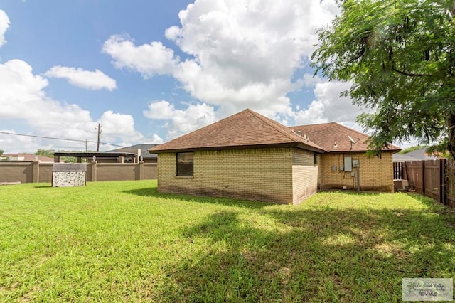 view of side of home with roof with shingles, a yard, a fenced backyard, central air condition unit, and brick siding