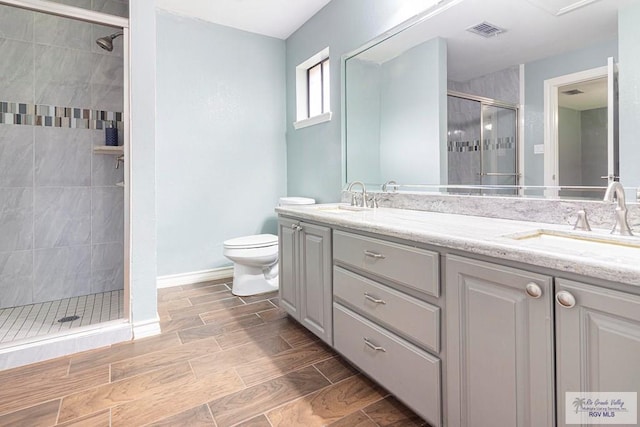bathroom with visible vents, toilet, a stall shower, a sink, and double vanity