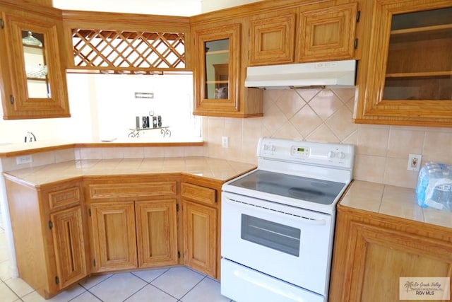 9165 Los Olmos Dr, Los Fresnos, TX 78566 - kitchen featuring white electric range, under cabinet range hood, tile countertops, and tasteful backsplash