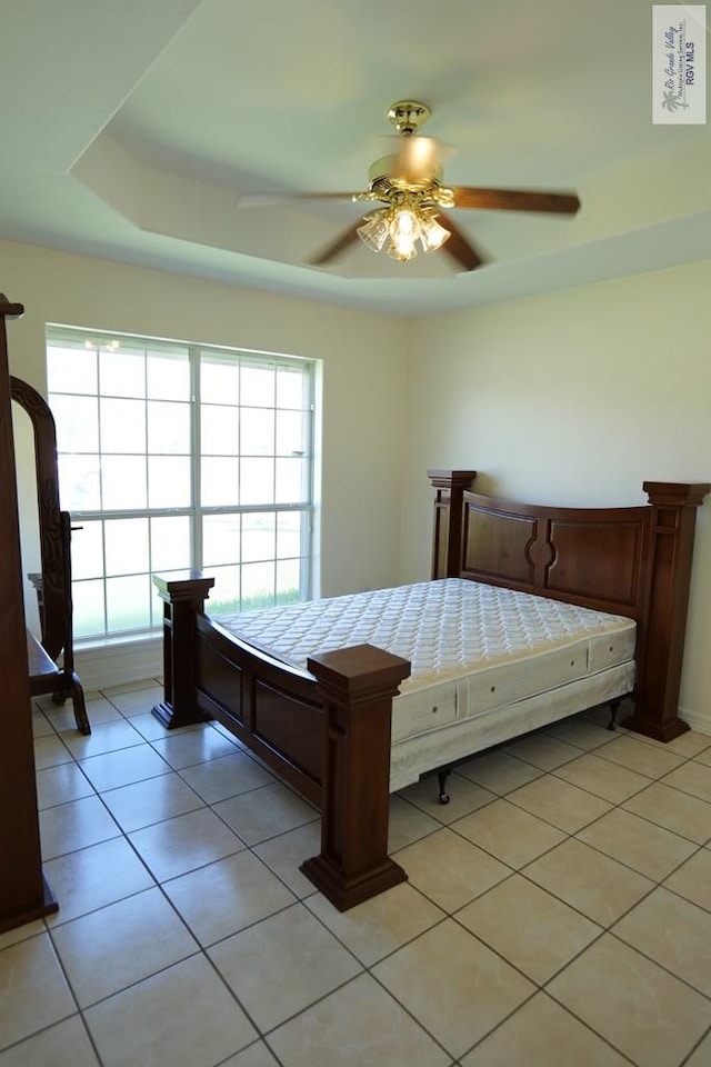 9165 Los Olmos Dr, Los Fresnos, TX 78566 - bedroom with multiple windows, light tile patterned floors, a ceiling fan, and a raised ceiling