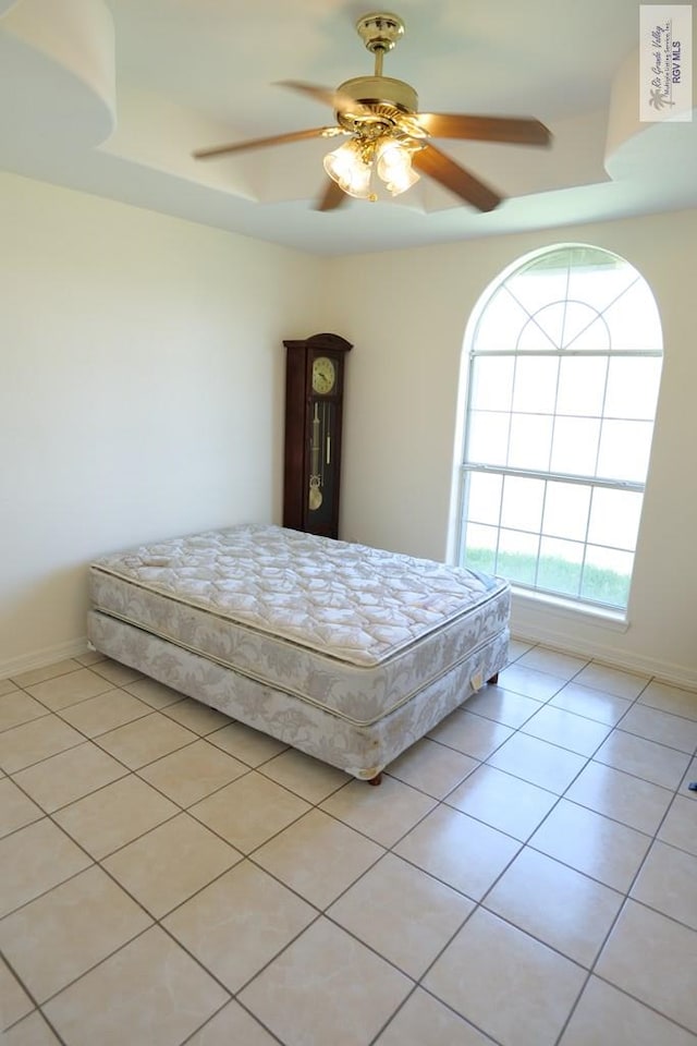 9165 Los Olmos Dr, Los Fresnos, TX 78566 - bedroom with light tile patterned flooring, ceiling fan, baseboards, and a raised ceiling