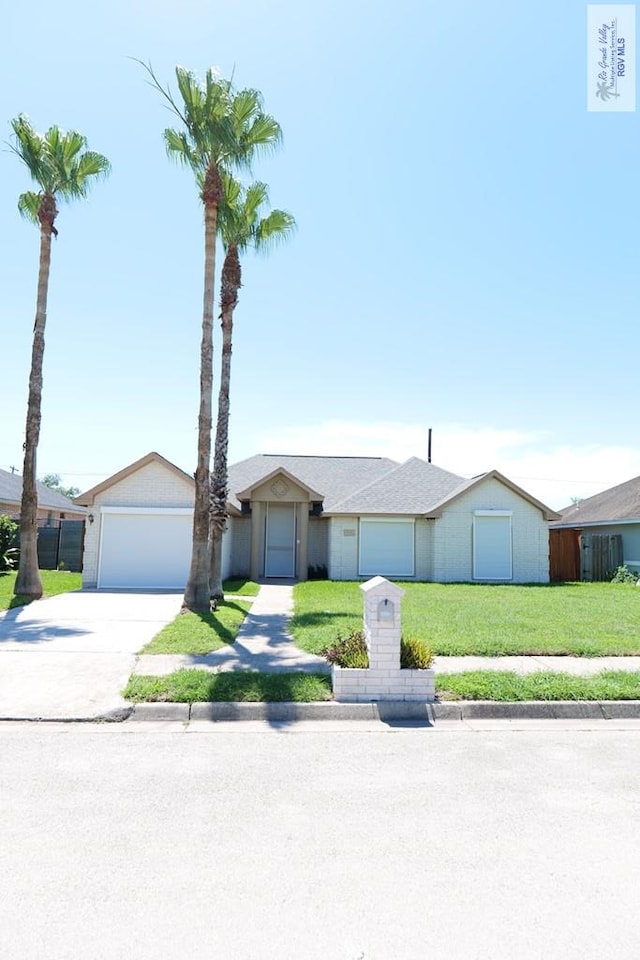 9165 Los Olmos Dr, Los Fresnos, TX 78566 - view of front of house with a garage, driveway, and a front yard
