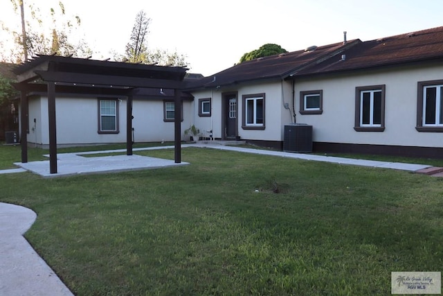 back of property with a lawn, a pergola, and central AC