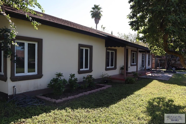 view of property exterior with a lawn and a patio area