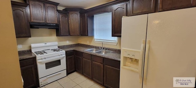 kitchen featuring light tile patterned floors, white appliances, dark brown cabinets, and sink