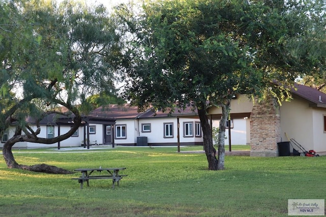 view of front of house with central AC unit and a front lawn