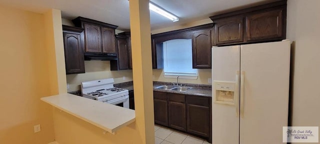 kitchen with dark brown cabinets, sink, light tile patterned floors, and white appliances