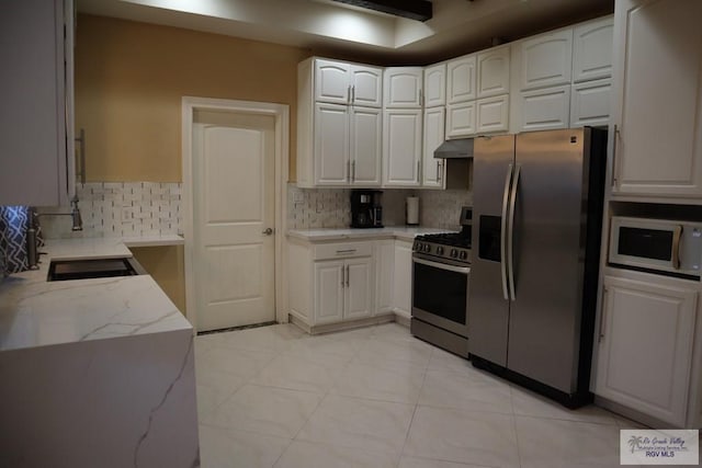 kitchen featuring backsplash, light stone counters, white cabinets, and stainless steel appliances