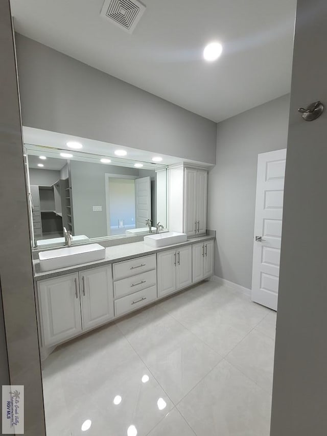 full bath with double vanity, a sink, and visible vents