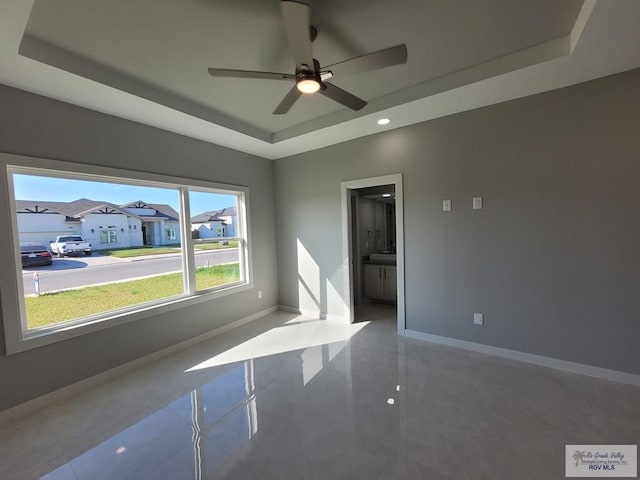 unfurnished room featuring a raised ceiling, baseboards, a ceiling fan, and recessed lighting