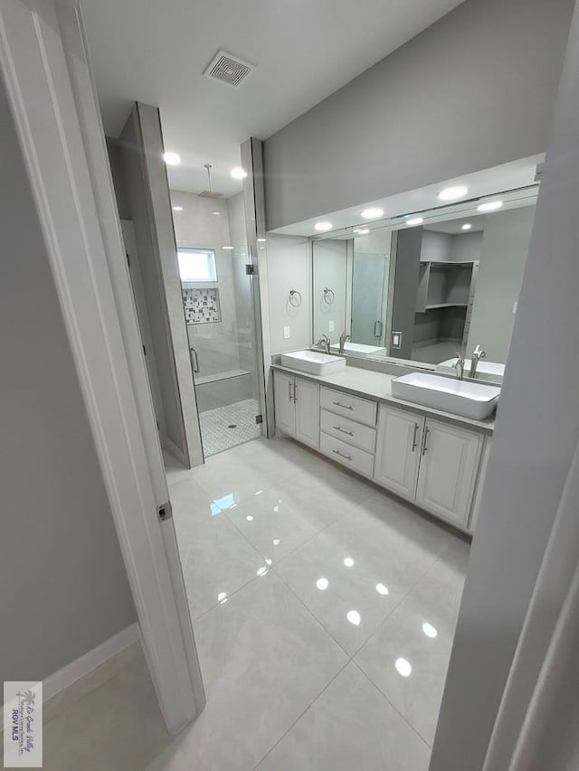 full bath with a sink, visible vents, double vanity, and a stall shower