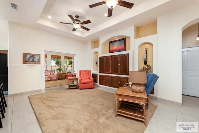 sitting room with a tray ceiling, ceiling fan, and light tile patterned floors